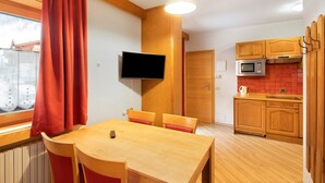 Une cuisine compacte avec des meubles en bois, un four à micro-ondes et un coin repas comprenant une table et des chaises.