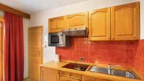 Une cuisine avec des meubles en bois, un four à micro-ondes, un évier et un dosseret de carrelage rouge.