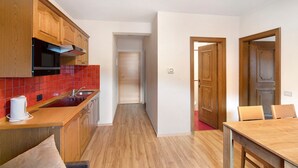 A kitchen with wooden cabinets, a microwave, and a red-tiled backsplash. - Holiday Apartment "Casa Marcos n 32" with Mountain View, Balcony & Wi-Fi (Livigno)