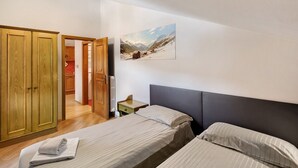 A bedroom with two beds, wooden wardrobe, and a painting on the wall. - Holiday Apartment "Casa Marcos n 35" with Mountain View, Balcony & Wi-Fi (Livigno)