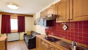 A compact kitchen with wooden cabinets, a microwave, and a sink. - Holiday Apartment "Casa Marcos n 35" with Mountain View, Balcony & Wi-Fi (Livigno)