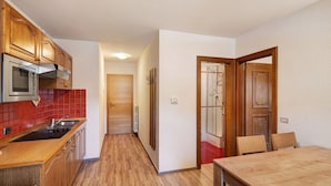 A kitchen with wooden cabinets, a microwave, and a red-tiled backsplash. - Holiday Apartment "Casa Marcos n 35" with Mountain View, Balcony & Wi-Fi (Livigno)