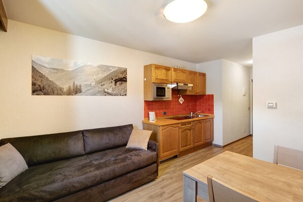 A modern kitchen with wooden cabinets, a microwave, and a red backsplash.