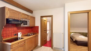 A compact kitchen with a microwave, kettle, and wooden cabinets. - Holiday Apartment "Casa Marcos n 36" with Mountain View, Balcony & Wi-Fi (Livigno)