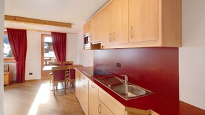 Una cucina moderna con mobili in legno, un lavello in acciaio inox e un piano di lavoro rosso.
