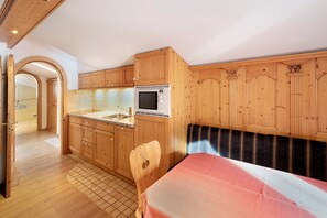 Une cuisine compacte avec des meubles en bois, un four à micro-ondes et un coin repas comprenant une table et un banc.