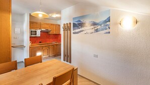 A modern kitchen with wooden cabinets, a red backsplash, and a dining area with a wooden table and chairs. - Holiday Apartment "Casa Marcos n 33" with Mountain View, Balcony & Wi-Fi (Livigno)
