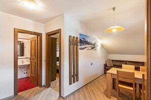 A room with a wooden dining table, a brown sofa, a ceiling light, and a wall-mounted picture.