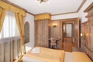 A bedroom with a bed, wooden wardrobe, and a desk with a chair.