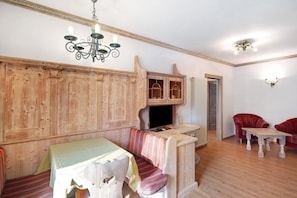 A room with a wooden bench, a table, a red armchair, and a small table with a lamp.