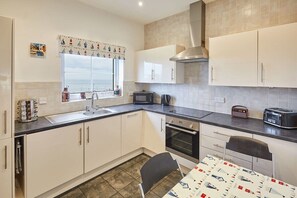 Compact kitchen with sink, microwave, toaster, and oven, plus a dining area with a chair.