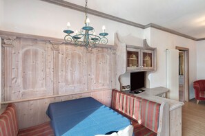 A room with a wooden wall panel, a bench, a table, a TV, and a red chair.