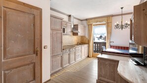Eine Küche mit Holzausstattung, einem eingebauten Backofen und einem Fenster mit Vorhängen.