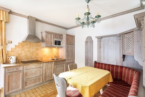 Une cuisine avec des meubles en bois, un four à micro-ondes et un banc recouvert d’une nappe jaune.