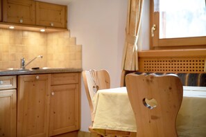 A kitchen with wooden cabinets, a sink, and a table with a tablecloth.