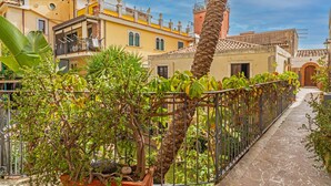 A narrow alleyway with a wrought iron fence, potted plants, and buildings with balconies and windows. - Apartment 'Casa Florio' with Shared Terrace, Wi-Fi and Air Conditioning (Taormina)