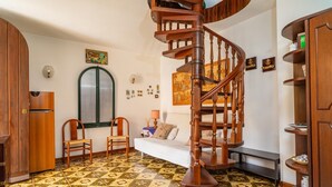 A room with a spiral staircase, a sofa, a wooden cabinet, and patterned floor tiles. - Apartment 'Casa Florio' with Shared Terrace, Wi-Fi and Air Conditioning (Taormina)