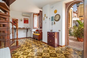 Eine Treppe führt zu einer Empore mit einem gemusterten Boden, einem Holzschrank und einem Blumentopf.