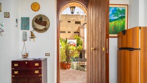 A hallway with a wooden door, a mirror, a small cabinet, and a painting on the wall. - Apartment 'Casa Florio' with Shared Terrace, Wi-Fi and Air Conditioning (Taormina)