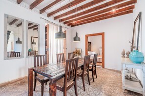 Un comedor con una mesa y sillas de madera, un lámpara colgante y un espejo en la pared.