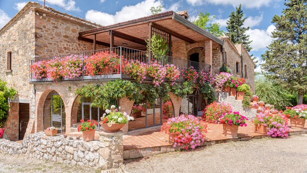 Ein Gebäude aus Stein mit Balkon, Bogenfenstern und Blumentöpfen.