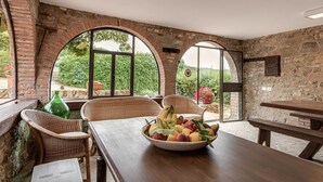 Ein rustikaler Essbereich mit Holztisch, Korbstühlen und einer Obstschale.