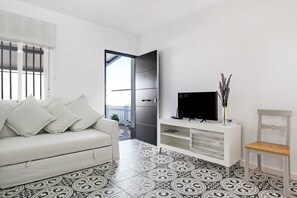 A modern living room with a sofa, TV, and decorative items.