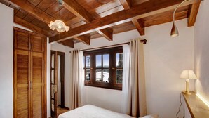 A bedroom with a wooden ceiling, a bed with white bedding, a window with curtains, and a bedside lamp. - Holiday Home "La Escalincha" with Mountain View, Shared Pool & Wi-Fi (Tegueste)