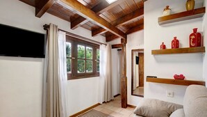 A room with a television, wooden beams, a window with curtains, a sofa, and shelves with decorative items. - Holiday Home "La Escalincha" with Mountain View, Shared Pool & Wi-Fi (Tegueste)