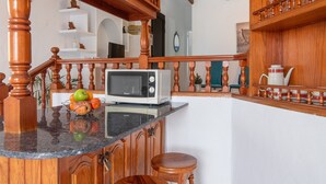 A kitchen with wooden cabinetry, a microwave, a fruit bowl, and a wooden staircase. - Holiday Home "Faro de Sardina Frente al Mar" with Sea View, Pool & Wi-Fi (Galdár)
