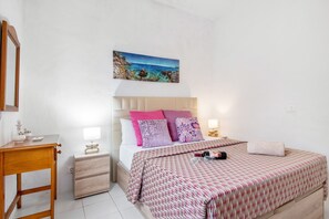 Une chambre à coucher avec un lit, des tables de chevet, une commode, un tableau et une fenêtre.
