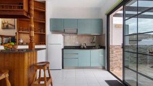 A kitchen with wooden cabinets, a refrigerator, a microwave, and a large window. - Holiday Home "Faro de Sardina Frente al Mar" with Sea View, Pool & Wi-Fi (Galdár)