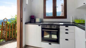 A kitchen with a built-in oven, a window with a view, and a wooden fence outside.