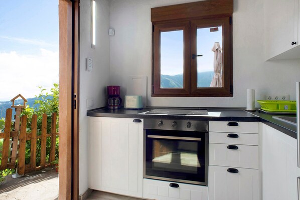 Una cocina con horno empotrado, ventana con vistas y valla de madera en el exterior.