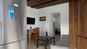 A modern kitchen with a stainless steel refrigerator, wooden dining table, and a flat-screen TV.