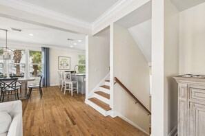 A spacious living area with a wooden floor, a dining table with chairs, a staircase, and a view of the outdoors. - Gulf View Home | Steps to Beach Access (Santa Rosa Beach)
