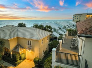 A coastal residential area with multiple buildings, a clear view of the ocean, and a well-maintained garden.