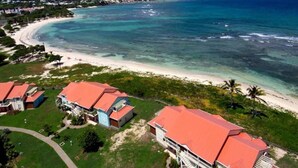 An aerial view of a coastal hotel with multiple buildings, a beach, and clear blue waters.