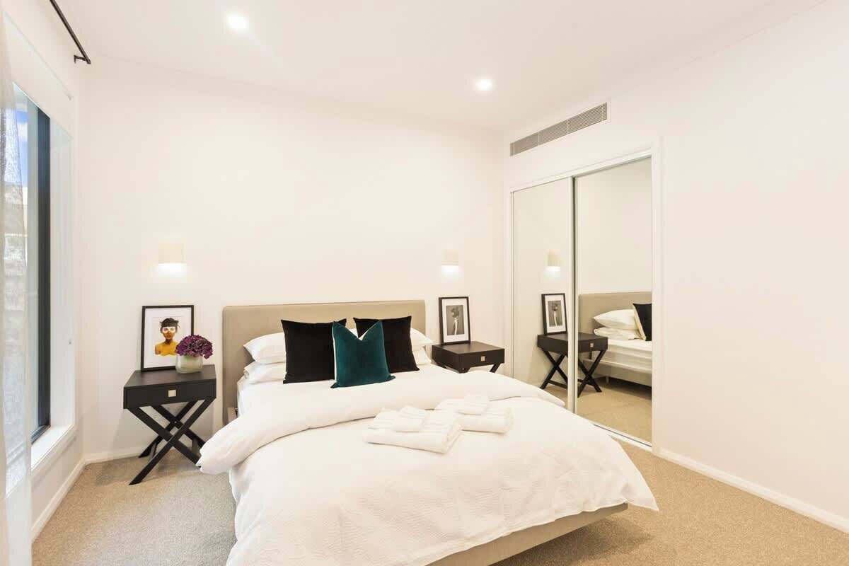 A hotel room with a large bed, a bedside table with a lamp, a mirror, and a window.