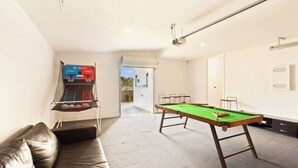 Una mesa de billar en una habitación con un sofá de cuero y una mesa de fútbolín.