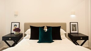Una habitaci ón de hotel con cama, dos mesitas de noche y cuadros enmarcados.