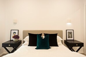 A hotel room with a bed, two nightstands, and framed pictures.