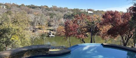 A swimming pool with a stone edge and a view of a lake and trees in the background.