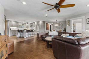 A modern kitchen with bar stools, a dining area with a leather sofa, and a ceiling fan. - SAN GABRIEL RIVER Retreat WATERFRONT Panoramic View PRIVATE POOL Outdoor Living! (Georgetown)