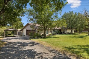 A residential property with a driveway leading to a garage, a covered porch, and a well-maintained lawn. - SAN GABRIEL RIVER Retreat WATERFRONT Panoramic View PRIVATE POOL Outdoor Living! (Georgetown)