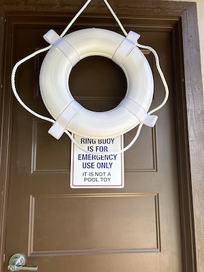 Uma porta com um círculo de bóia branco e uma placa indicando uso exclusivo para emergências.