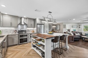A modern kitchen with a central island, stainless steel appliances, and a herringbone wood floor. - SAN GABRIEL RIVER Retreat WATERFRONT Panoramic View PRIVATE POOL Outdoor Living! (Georgetown)