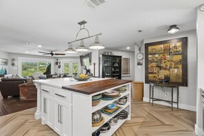 A modern kitchen with a central island, white cabinetry, and a variety of cookware.