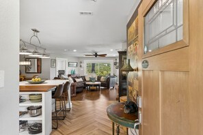 A spacious kitchen with a dining area, wooden flooring, and a ceiling fan.