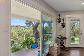 A room with a sliding glass door leading to a balcony with a view of a tree and a pond.